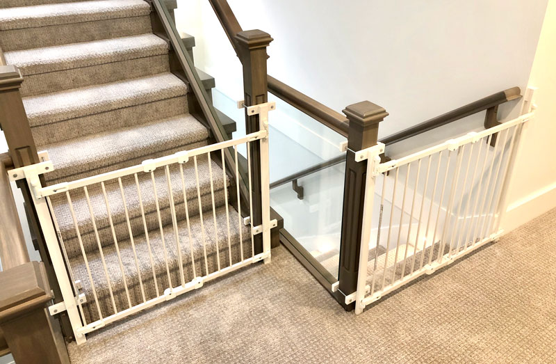 Two safety gates secured to wooden staircase posts with the no-hole clamp system — no drilling into the posts